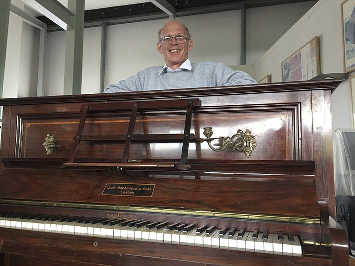 Piano tuner Martin Backhouse with the piano where he found a stash of gold, smiles in Ludlow Museum in Ludlow, England Thursday April 20, 2017, As a mystery surrounds the identity of the rightful heirs to a treasure trove of gold coins.


