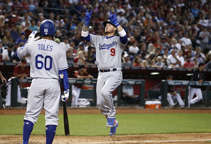 Los Angeles Dodgers’ Yasmani Grandal (9) celebrates his two-run home run against the Arizona Diamondbacks as Dodgers’ Andrew Toles (60) waits to give a high-five during the fifth inning of a baseball game Sunday, April 23, in Phoenix.