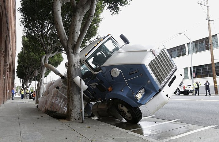 A big rig truck is stuck in a sinkhole in San Francisco, Friday, May 5, 2017. A truck driver escaped unharmed early Friday after a massive sinkhole started swallowing his big rig on a San Francisco street. (AP Photo/Jeff Chiu)
