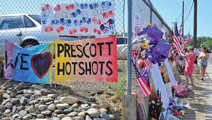 People look and add items to the memorial to the 19 Granite Mountain Hotshots outside of Station 7 in days following the deaths of 19 firefighters.