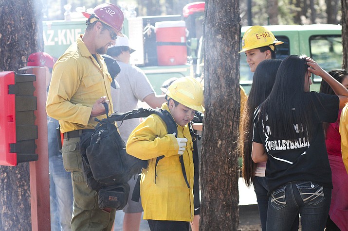 A Williams Middle School student tries on fire gear during a school field trip to the Williams Ranger District office May 4. 