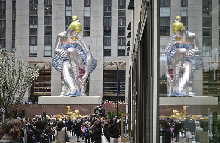 “Seated Ballerina”, center, the public art exhibition of a 45-foot tall inflatable nylon sculpture depicting a seated ballerina from artist Jeff Koons’ Antiquity series, is displayed at Rockefeller Center after it was unveiled Friday May 12, 2017, in New York. (AP Photo/Bebeto Matthews).
