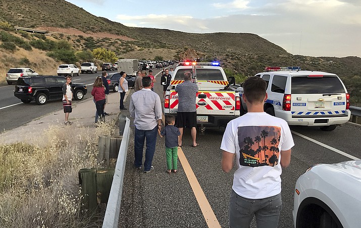 In this Sunday, May 14, 2017 photo, travelers take a break after a pair of collisions brought traffic to a standstill for some five hours on Interstate 17 near Black Canyon City, Ariz. (Brian Swanton via AP)