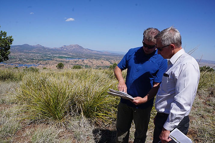 Prescott Trails and Natural Parklands Coordinator Chris Hosking, left, and Prescott Valley Public Works Director Norm Davis, right, discuss possible routes for connecting trails at the top of Glassford Hill. The two met at summit this week, with views of Watson Lake and Granite Mountain in the background. (Cindy Barks/Courier)