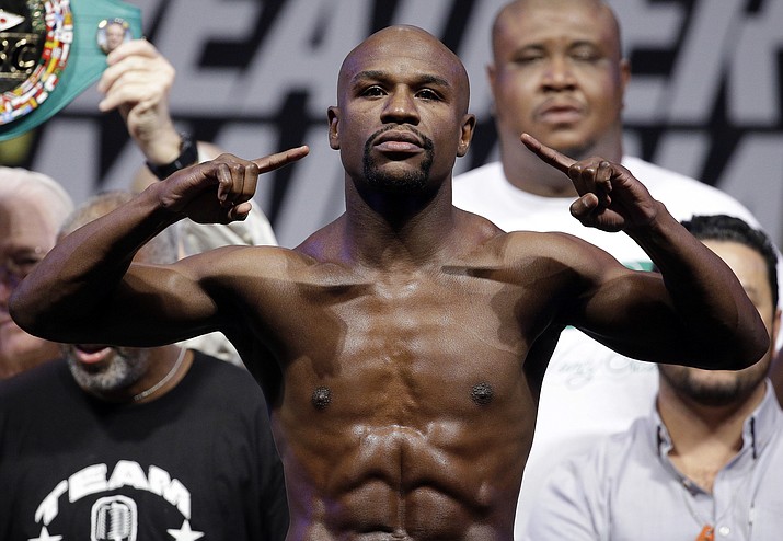 In this 2014, file photo, Floyd Mayweather Jr. poses on the scale. Mayweather Jr. said Wednesday, June 14, he will come out of retirement to face UFC star Conor McGregor in a boxing match on Aug. 26. (John Locher, AP file)
