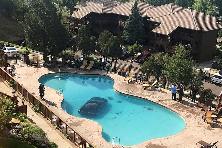 a car sits in a pool after a woman escaped injury when she hit the gas pedal instead of the brakes and ended up in the pool at the Cheyenne Mountain Resort, in Colorado Springs, Colo., on Monday morning, July 3, 2017. (Kyla Galer/KKTV 11 via AP)
