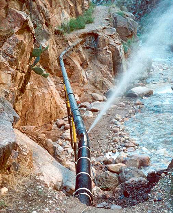 This undated photo shows water spraying from a break in an exposed section of the Grand Canyon trans-canyon waterline, originally covered under a path, after a flash flood event. Park officials plan to replace at least part of the decades-old and problem-plagued pipeline that plunges down into the canyon and back up the other side to supply water to South Rim hotels, campgrounds and other facilities at the northern Arizona park. (National Park Service via AP)