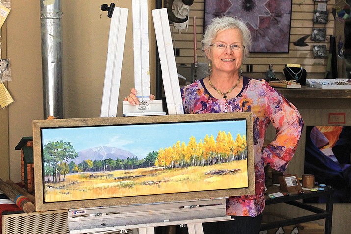 Mary Minnich displays one of her landscape paintings. Minnich is the owner of Our Mountain Home Gallery on Route 66.