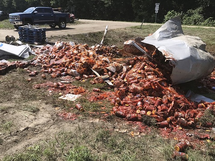 Broken jars of spaghetti sauce litter a road near Camden, Ark. The crash marked the third time this month that edible goods were left on an Arkansas highway. (Shantelle Laughlin/Camden News via AP)
