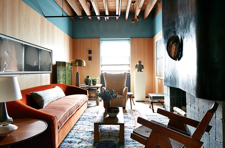 This April 2017 photo provided by Stephen Kent Johnson shows Neal Beckstedt's space at the Kip's Bay Show House in New York. This spring Beckstedt clad his space in oak veneer, but brought it within about a foot of the ceiling, then applied a thick band of teal lacquer the rest of the way. Bold hues and warm textures set the stage for home dÃ©cor that's got drama, yet is very livable. (Stephen Kent Johnson via AP)