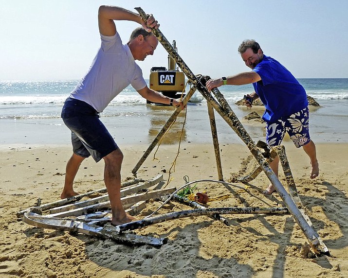 Peter Brockmann, left, president of the East Beach Association, gets help assembling pieces of a mystery object that was removed from the surf on East Beach in Westerly, R.I. The circular metal object was discovered off shore at the beach last month near singer Taylor Swift’s oceanfront mansion, and it’s much bigger than originally thought before it was excavated. (Harold Hanka/The Sun via AP)

