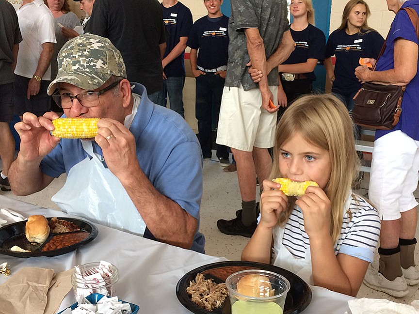 Prescott residents Juan Mendez and his granddaughter, Juliette Zaun, 6, chow down on corn at the Chino Valley Corn Dinner Sept. 2.  Juliette said she's been coming to this annual event "since I was a baby." (Sue Tone/Review)