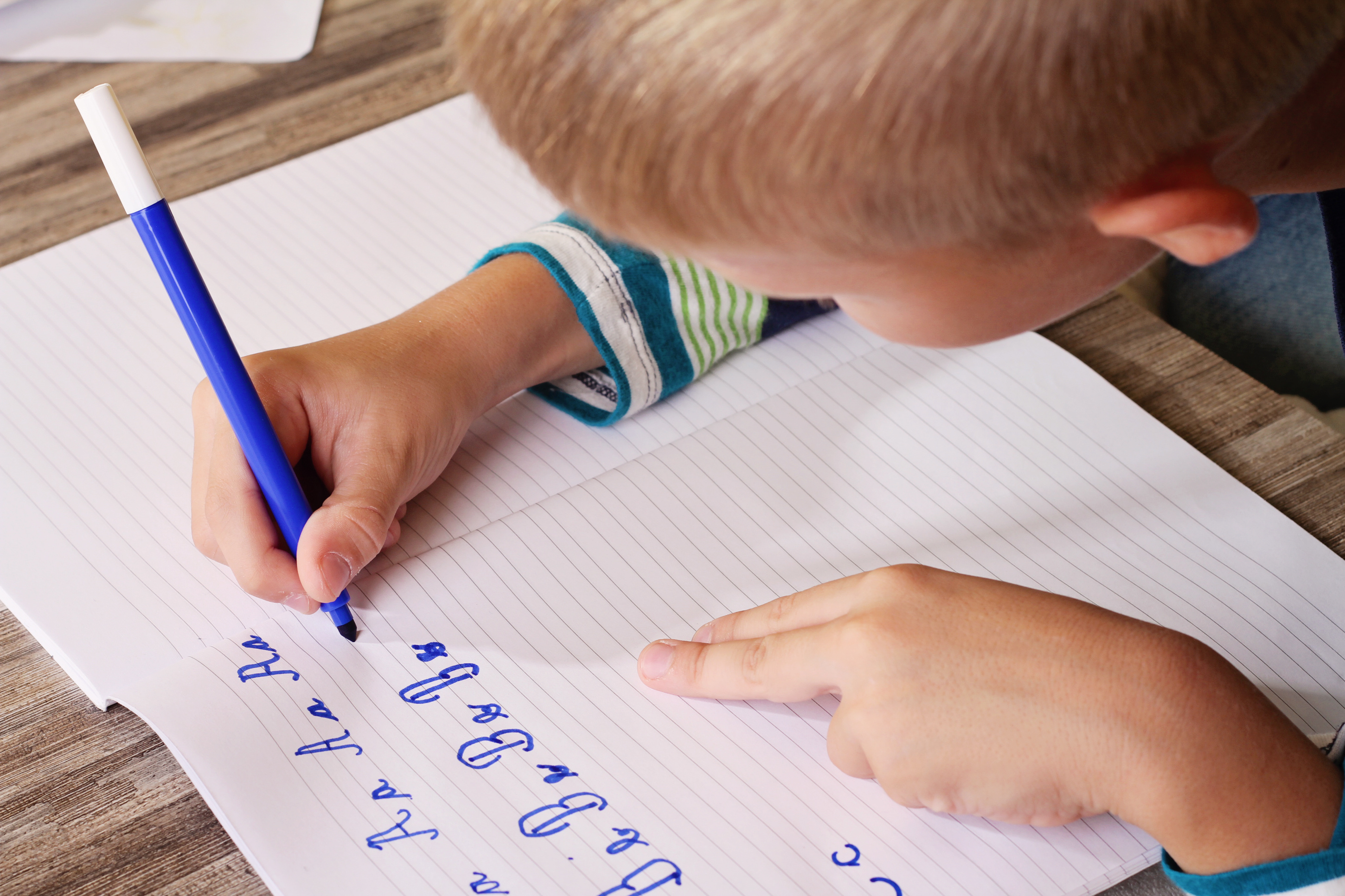 Написано с большей частью. Ребенок пишет. Ребенок пишет в тетради. Ребенок учится писать. Ребенок пишет ручкой.