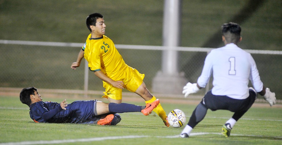 Yavapai's Jose Perez Flores (25) gets taken down as he takes a shot on goal as the Roughriders take on Pima Community College in soccer Tuesday night in Prescott Valley. (Les Stukenberg/Courier)