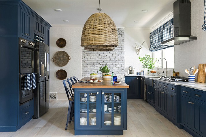 This 2017 photo provided by Scripps Networks, LLC shows a kitchen designed by Brian Patrick Flynn. The kitchen features a L-shaped perimeter design with lower cabinets painted a rich shade of navy blue, a style choice that has become increasingly popular in recent months. (Photos by Robert Peterson, Rustic White Photography/Scripps Networks, LLC via AP)