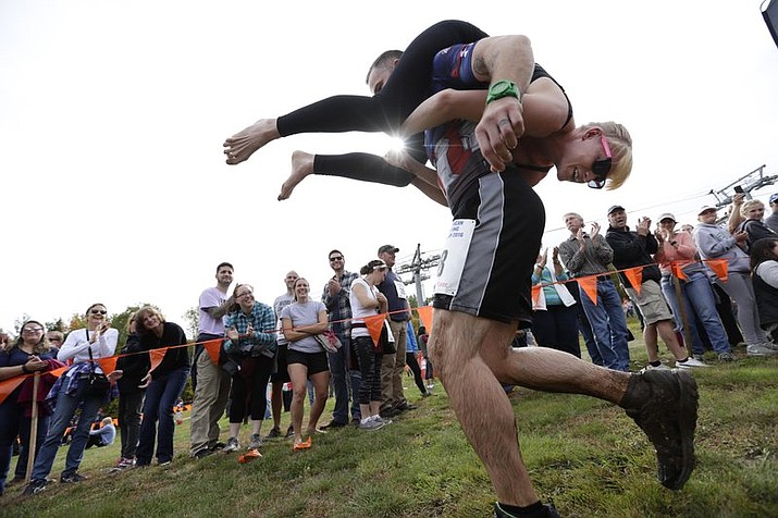 Jaime Devine is carried by her husband, Thomas Devine, of Boston, Mass., during the North American Wife Carrying Championship at the Sunday River Ski Resort in Newry, Maine. Dozens of participants are vying for cash and beer in the North American Wife Carrying Championship. (AP Photo/Robert F. Bukaty, File)