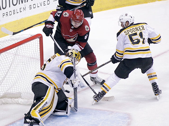 Boston Bruins goalie Anton Khudobin, left, makes a save on the shot by Arizona Coyotes' Lawson Crouse (67) as Boston Bruins' Ryan Spooner skates in to defend during the second period of an NHL hockey game, Saturday, Oct. 14, 2017, in Glendale, Ariz. (AP Photo/Ralph Freso)

