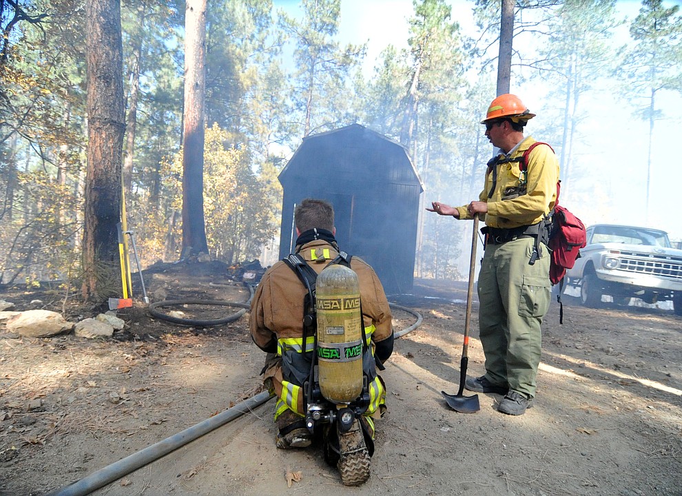 GRoom Creek firefighters look at the burned shed as fire crews work the one-acre Empire Fire in Groom Creek Tuesday afternoon. (Les Stukenberg/Courier)