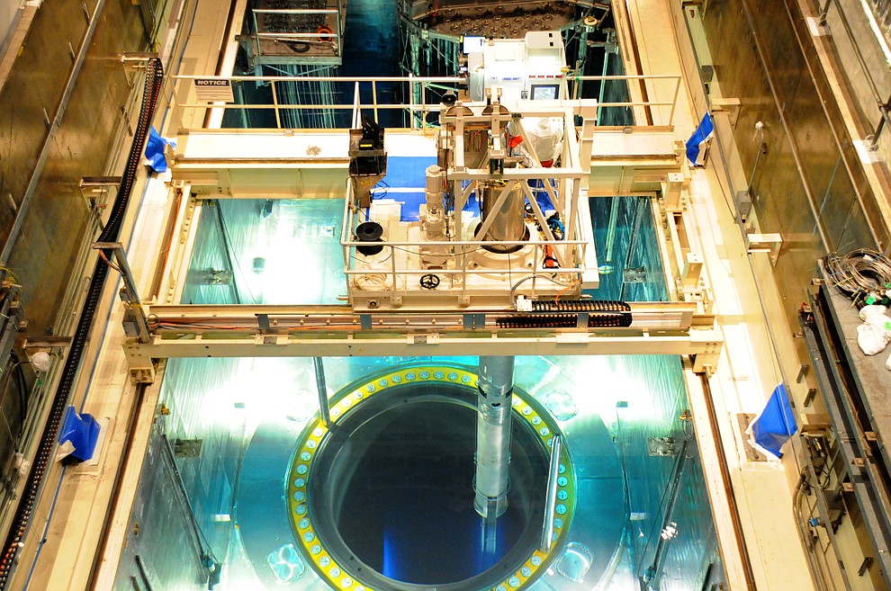 The deep blue of Cherenkov radiation reveals the location of the fuel assemblies within the open reactor core (foreground). The tube beneath the platform, a tube-shaped fuel handling machine extracts one of these assemblies. (APS/Courtesy)