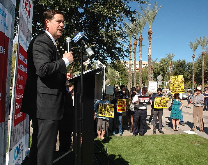 Gov. Doug Ducey touts the concept — but not the specifics — of the Republican tax plan Monday, Nov. 6, 2017, at the state capitol as protesters state their case that it is simply relief for corporations and the wealthy. (Howard Fischer/Capitol Media Services)