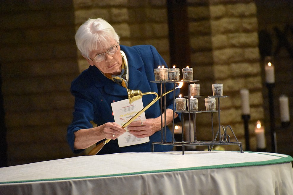 Sister Anne Fitzsimons lights candles representing different faiths during the interfaith Celebration of Thanks event on Nov. 16, 2017 at Sacred Heart Church in Prescott. (Richard Haddad/WNI)