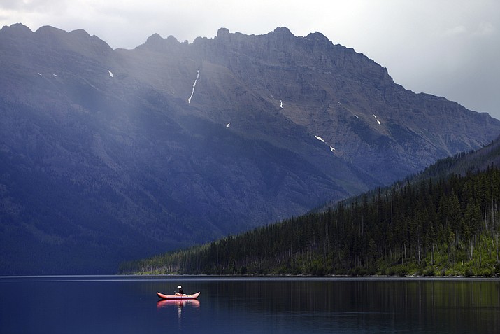 A lone fisherman glides along on Kintla Lake in North Glacier National Park, Mont. A group of state attorneys general on Wednesday, Nov. 22, 2017, urged the National Park Service to scrap its proposal to more than double the entrance fee at 17 popular national parks. (Brenda Ahearn/The Daily Inter Lake via AP, File)
