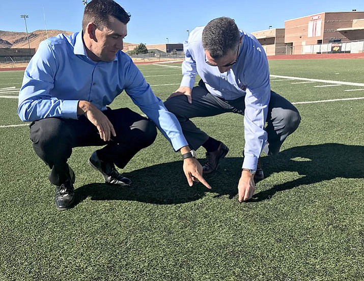 School Superintendent Dan Streeter, left, points out the rubber pellets that are exposed in the worn areas of turf on the Bradshaw Mountain High School football field. The district is looking at replacing the synthetic turf on the baseball and football fields. (Sue Tone/Tribune)