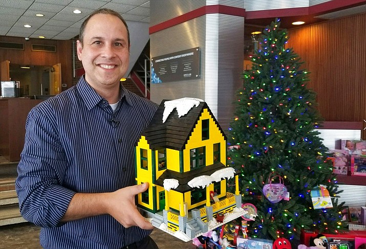 In this Dec. 12, 2017 image from video provided by WSTM-TV, Jason Middaugh poses with a model of the house from "A Christmas Story" at his home in Marcellus, N.Y. (WSTM-TV via AP)