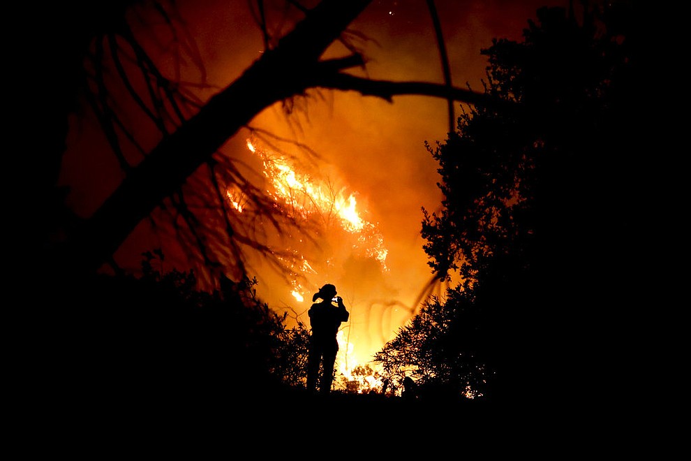 A firefighter takes a cell phone picture during a wildfire Saturday, Dec. 16, 2017, in Montecito, Calif. The so-called Thomas Fire is now the third-largest in California history. (AP Photo/Chris Carlson)