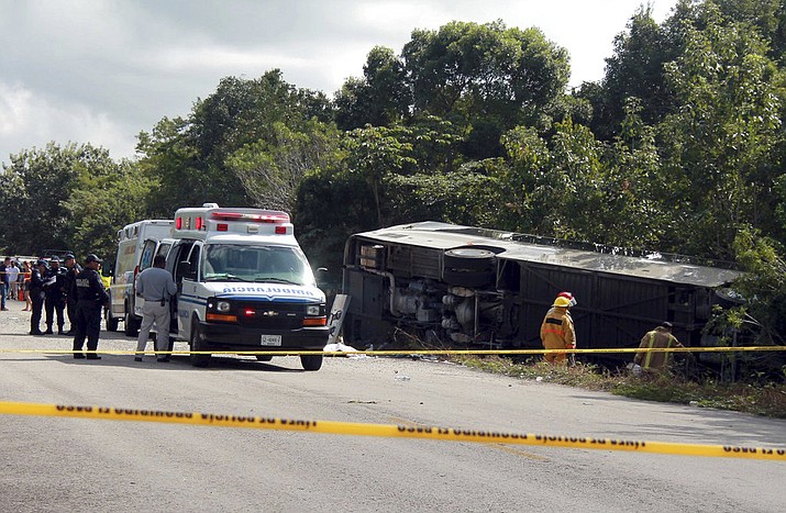 An ambulance sits parked next to an overturned bus in Mahahual, Quintana Roo state, Mexico, Tuesday, Dec. 19, 2017. The bus carrying cruise ship passengers to the Mayan ruins at Chacchoben in eastern Mexico flipped over on a highway early Tuesday. (Novedades de Quintana Roo via AP)
