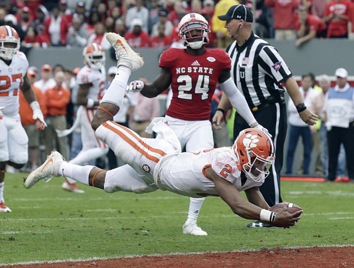 In this Nov. 4, 2017, file photo, Clemson quarterback Kelly Bryant (2) dives into the end zone for a touchdown while North Carolina State’s Shawn Boone (24) looks on in Raleigh, N.C. (Gerry Broome/AP, File)