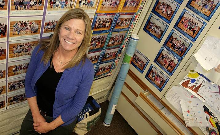 Cheryl Kessel, a second grade teacher at Clarkdale-Jerome School, poses with classroom photos from all the years she has taught at the school. (Photo by Bill Helm)