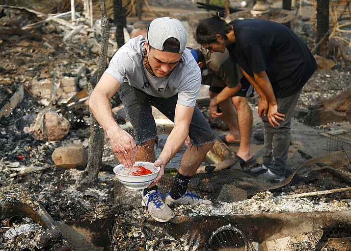 FILE - In this file photo, photo Logan Hertel fills a bowl of goldfish with water after he and some friends rescued them from a destroyed home on Parker Hill Court in Santa Rosa, Calif. Hertel is determined to reunite them with their owners. (Nhat V. Meyer/San Jose Mercury News via AP)
