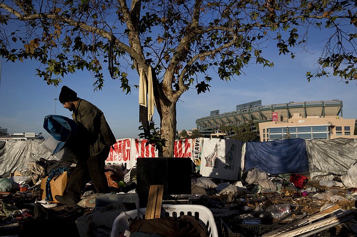 Homeless Junior Sanchez, 29, carries a tarp he found in a pile of trash in a homeless encampment on the Santa Ana River trail near Angel Stadium Saturday, Dec. 2, 2017, in Anaheim, Calif. "Toughest part being homeless is getting a plate of food and a shower," said Sanchez who said he became homeless after losing his job as cook. (AP Photo/Jae C. Hong)
