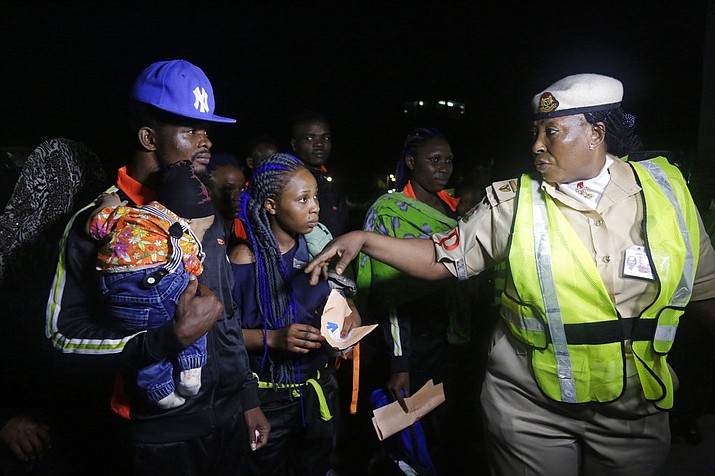 FILE - In this file photo, an unidentified immigration officer, right, speaks to Nigerian returnees from Libya upon arrival at the Murtala Muhammed International Airport in Lagos, Nigeria. An emergency effort has begun to repatriate thousands of migrants stranded in camps across Libya, but now the returnees are posing a challenge.  (AP Photo/Sunday Alamba, File)

