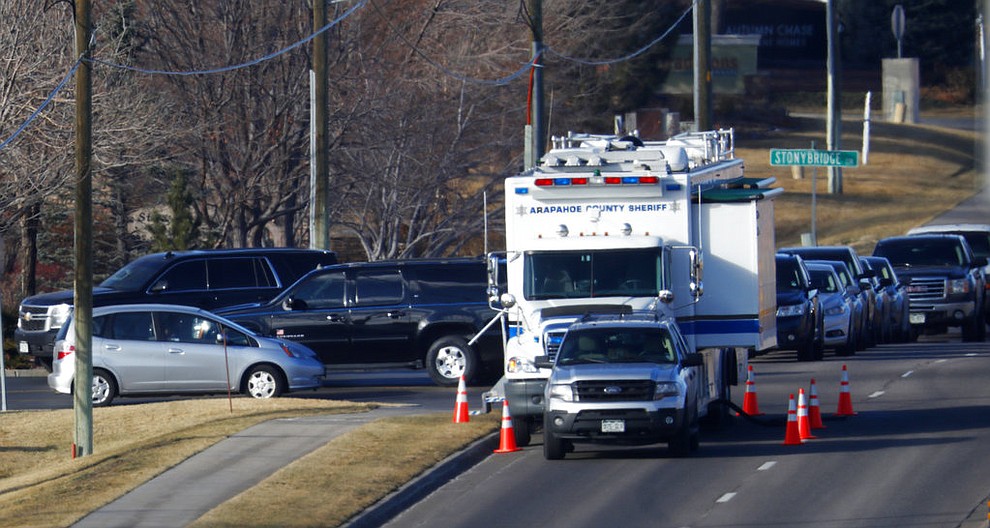 A long line of police vehicles stand on County Line Road near the scene of shooting Sunday, Dec. 31, 2017, in Highlands Ranch, Colo. Authorities in Colorado say one deputy has died and multiple others were wounded, along with civilians, in a shooting that followed a domestic disturbance in suburban Denver. (AP Photo/David Zalubowski)