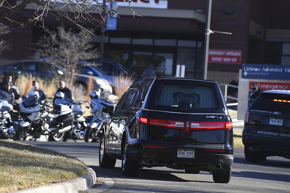 A hearse arrives at Littleton Hospital as officers from various police agencies line up for a procession for an officer who was fatally wounded in a domestic incident in a Highlands Ranch apartment complex in Denver, Sunday, Dec. 31, 2017. Multiple other police officers and civilians were also wounded. (John Leyba/The Denver Post via AP)
