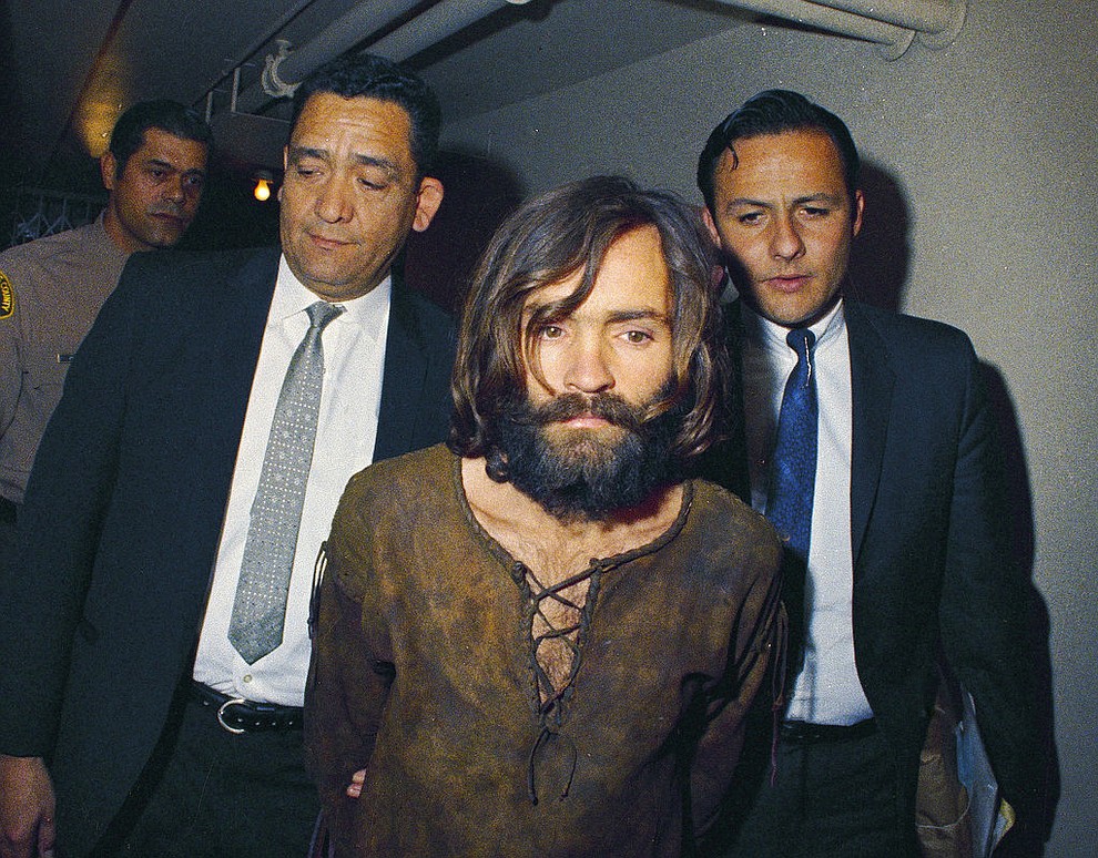 FILE - In this 1969 file photo, Charles Manson is escorted to his arraignment on conspiracy-murder charges in connection with the Sharon Tate murder case. The hippie cult leader who became the hypnotic-eyed face of evil across America after orchestrating the gruesome murders of the pregnant actress and six others in Los Angeles during the summer of 1969 was among the notable figures who died in 2017. (AP Photo, File)