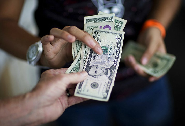 FILE - In this June 6, 2015, file photo, a customer, bottom, pays for goods while shopping at the Atlanta Farmers Market in Atlanta. U.S. President Donald Trump appears to believe that his tax cuts will start an economic renaissance. (AP Photo/David Goldman, File)
