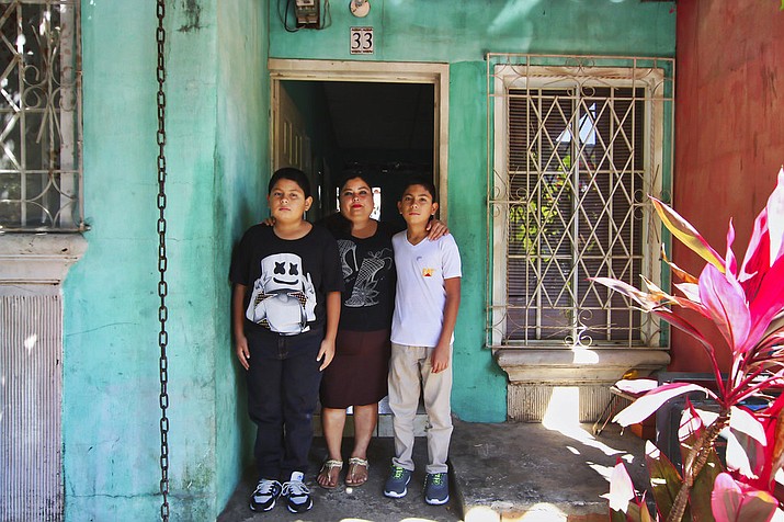 Flor Tovar and her two sons Christian, right, and Omar Elias, left, pose for a photo at their home in Ciudad Real, El Salvador, Tuesday, Jan. 9, 2018. Tovar receives a lifeline every two weeks in the form of wired cash from her husband living in the United States. (AP Photo/Salvador Melendez)

