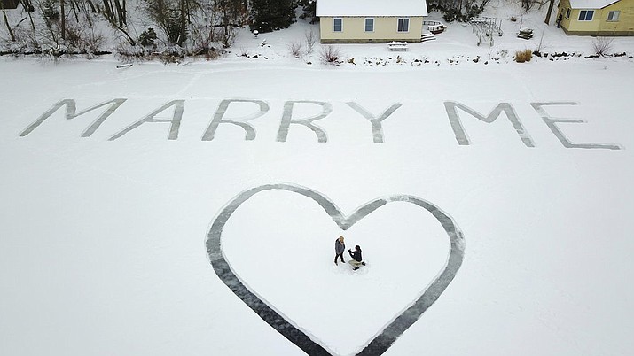 In this Jan. 7, 2018 photo provided by Ed Becker, Gavin Becker proposes to his long-time girlfriend Olivia Toft on Eight Crow Wing Lake near Nevis, Minn. Becker had his family's help etching out the big question with a snow blower in 25-foot-tall letters and a huge heart in the snow on the frozen lake. (Ed Becker via AP)
