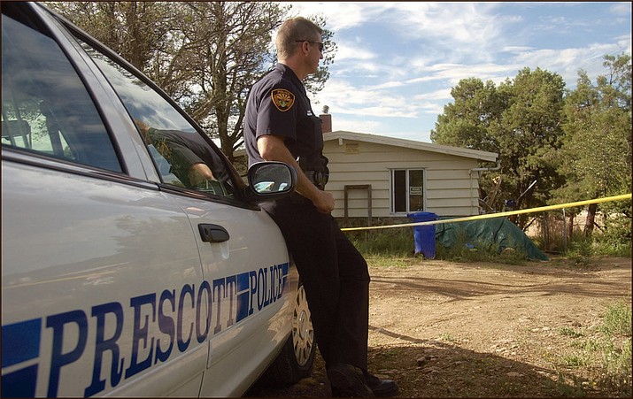 Prescott Police Officer Robert Peoples watches over the house in the 1100 block of Willow Creek Road where police arrested Edwin Rowlette this morning. (Les Stukenberg/Courier)