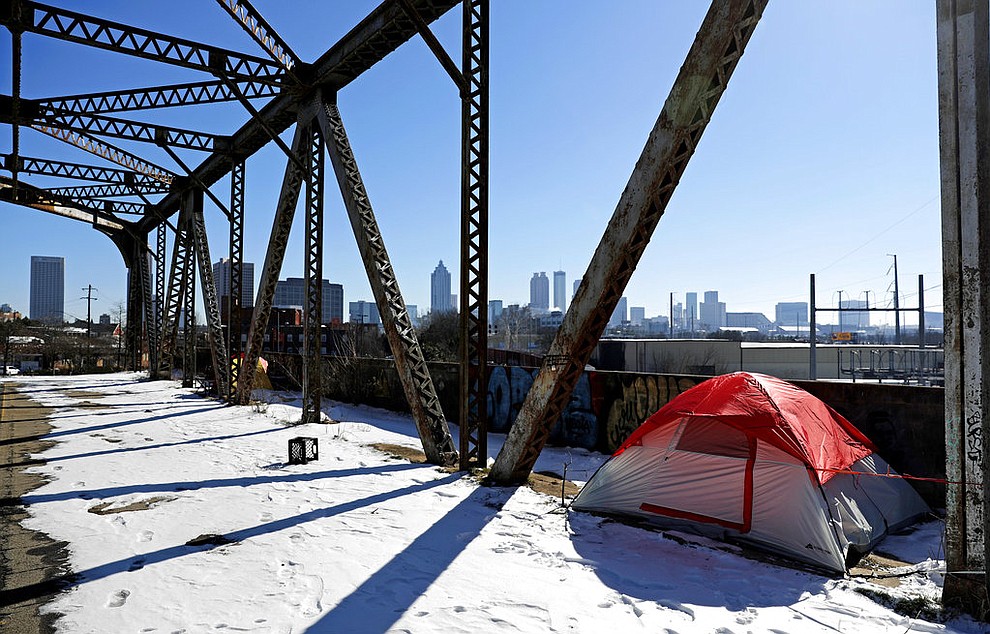 A tent sits in the snow on a bridge frequented by the homeless as the downtown skyline stands in the background in Atlanta, Thursday, Jan. 18, 2018. The deep freeze that shut down much of the South began to relent Thursday as crews worked to clear roads blanketed by a slow-moving storm that left ice and snow in places that usually enjoy mild winters. (AP Photo/David Goldman)