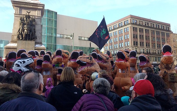 People dressed in inflatable Tyrannosaurus rex dinosaur costumes participate in a rally in Portland, Maine, Saturday, Jan. 20, 2018. (AP Photo/Patrick Whittle)