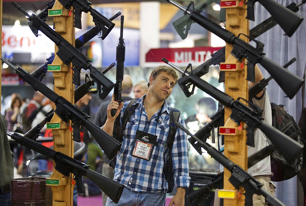 FILE - In this Jan. 17, 2013, file photo, Michael Kiefer, of DeFuniak Springs, Fla., checks out a display of rifles at the Rock River Arms booth during the 35th annual SHOT Show in Las Vegas. The largest gun industry trade show will be taking place in Las Vegas Jan. 23-26 just a few miles from where a gunman carried out the deadliest mass shooting in modern U.S. history. (AP Photo/Julie Jacobson, File)