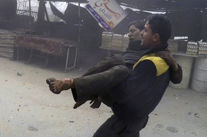 This photo provided by the Syrian Civil Defense group known as the White Helmets, shows a civil defense worker carrying a wounded man after airstrikes hit a rebel-held suburb near Damascus, Syria, Monday, Feb. 5, 2018. The Syrian Observatory for Human Rights says waves of airstrikes hit at least five neighborhoods in the Eastern Ghouta suburb, the only remaining rebel stronghold near the capital, Damascus. (Syrian Civil Defense White Helmets via AP)

