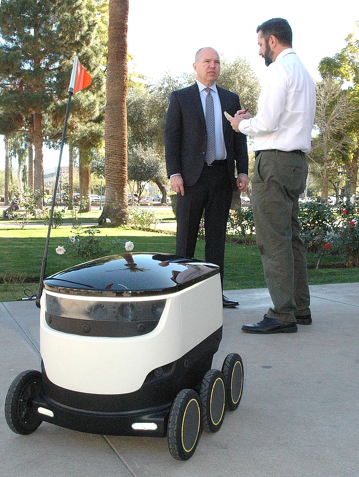 At left, David Catania, spokesman for Starship Technologies, explains how an autonomous robot, pictured, could be used to deliver everything from groceries and prescriptions to mail. (Howard Fischer/Capitol Media Services)