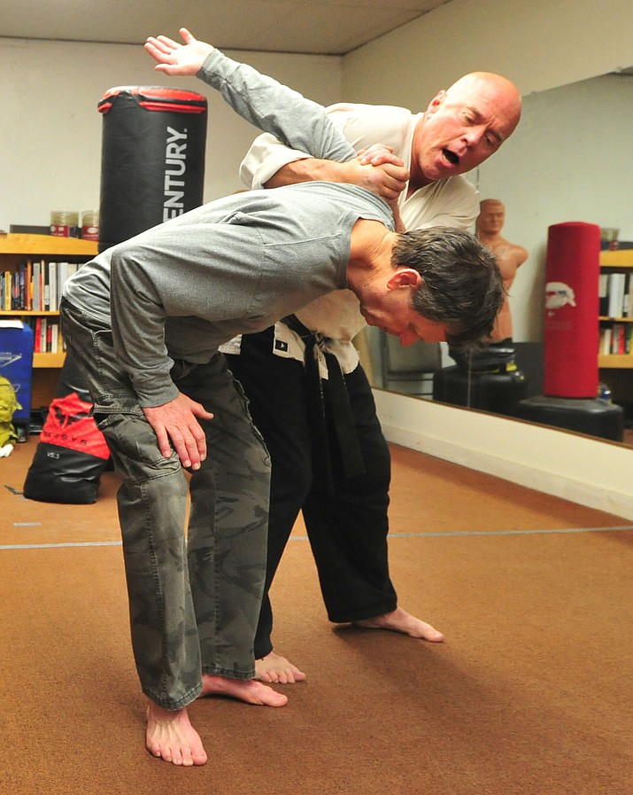 Real World Self Defense’s Mark Bryans, at right, works with client Mike Russell before class on Thursday at Champions Gym in Prescott.  (Les Stukenberg/Courier)