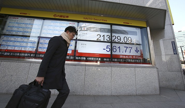 A man walks by an electronic stock board of a securities firm in Tokyo, Friday, Feb. 9, 2018. Asian shares have opened lower and are tracking the overnight plunge on Wall Street. The Dow Jones industrial average plunged more than 1,000 points as a weeklong market swoon continued. (AP Photo/Koji Sasahara)

