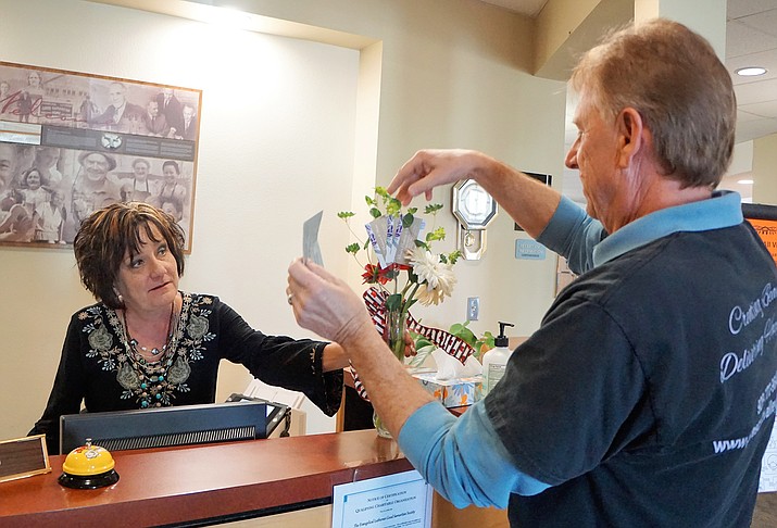 Flower deliveryman David Smith, right, drops off a complimentary arrangement to Lynda Duffy, receptionist at Good Samaritan rehabilitation center in Prescott Valley. In preparation for Valentine’s Day, Smith recently delivered a number of bouquets to regular customers of the Prescott Valley Florist shop. (Cindy Barks/Courier)